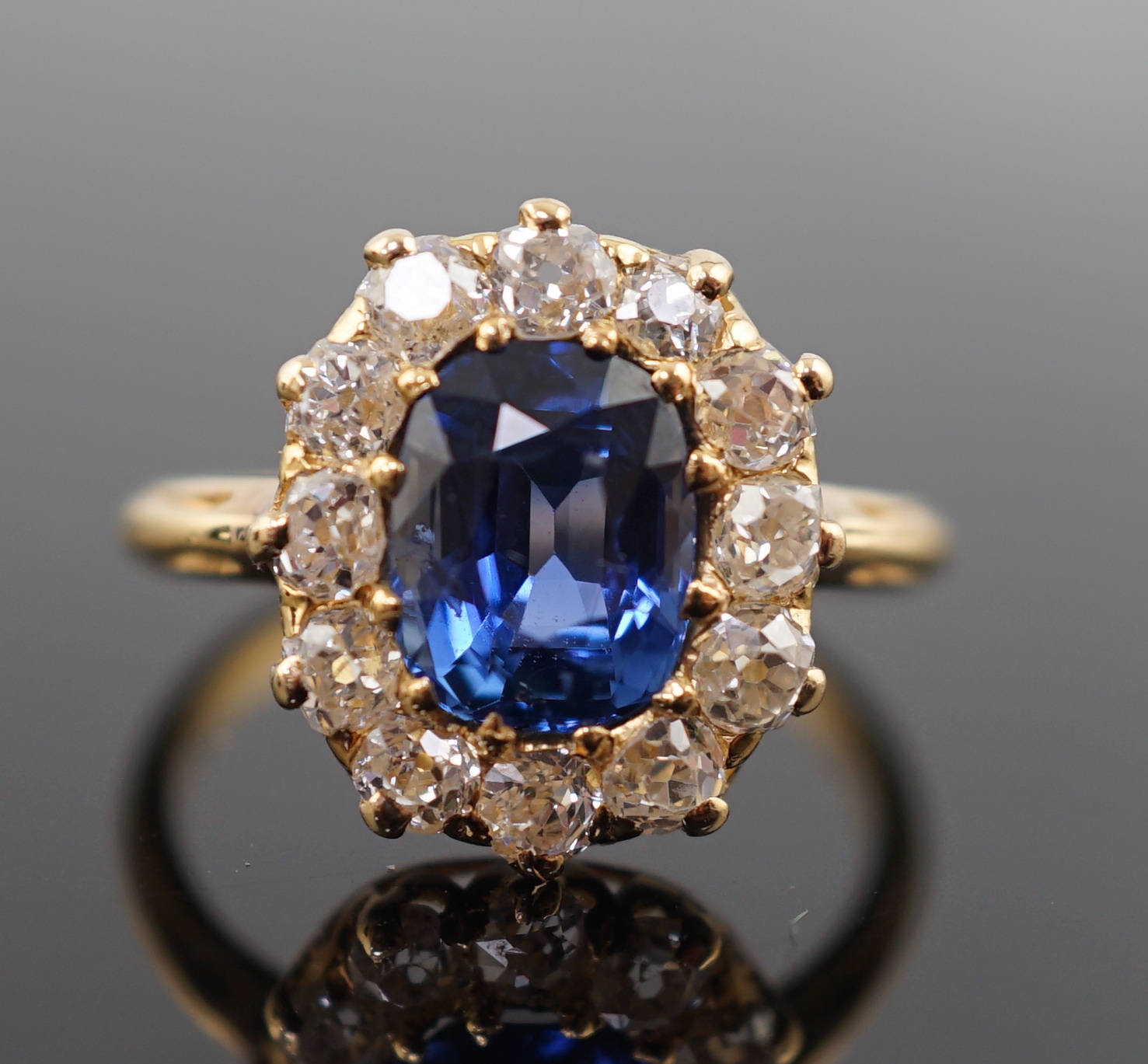 A gold, sapphire and old round cut diamond set oval cluster ring